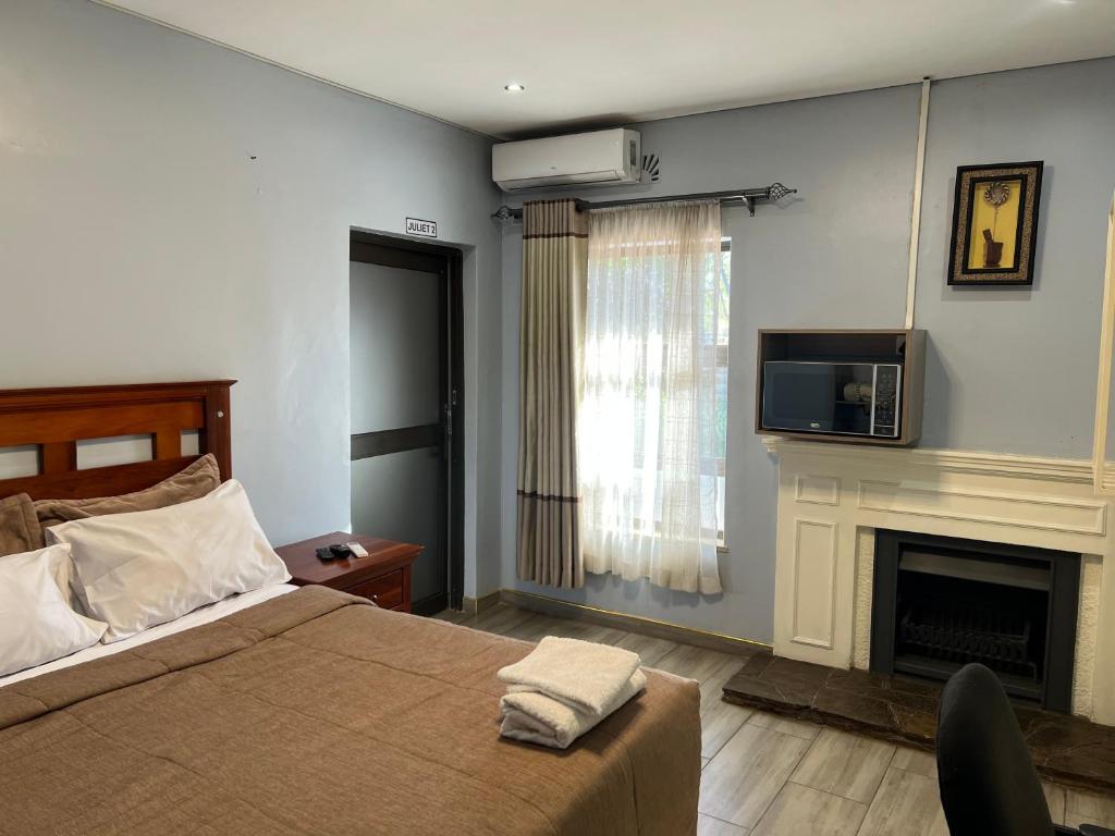 a bedroom with a bed with a fireplace and a tv at Nduna Legacy Lodge in Harare