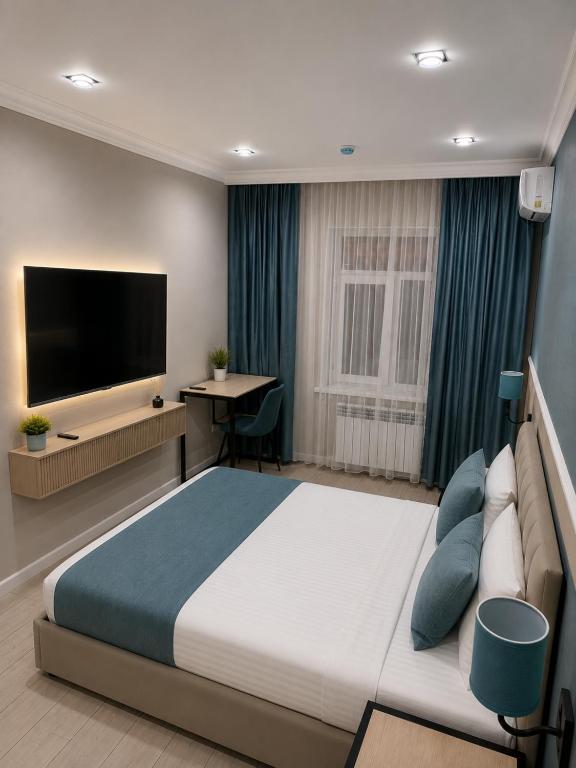 a bedroom with a large bed and a flat screen tv at Aqua Hotel in Bishkek