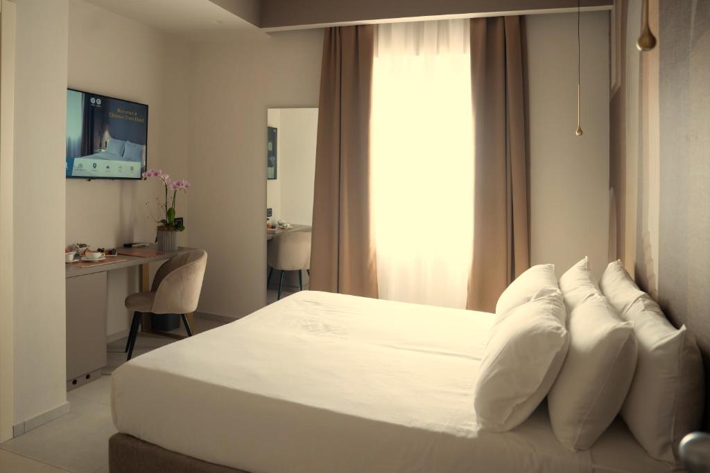 a bedroom with a white bed with white pillows at Didimos Town Hotel in Reggio di Calabria