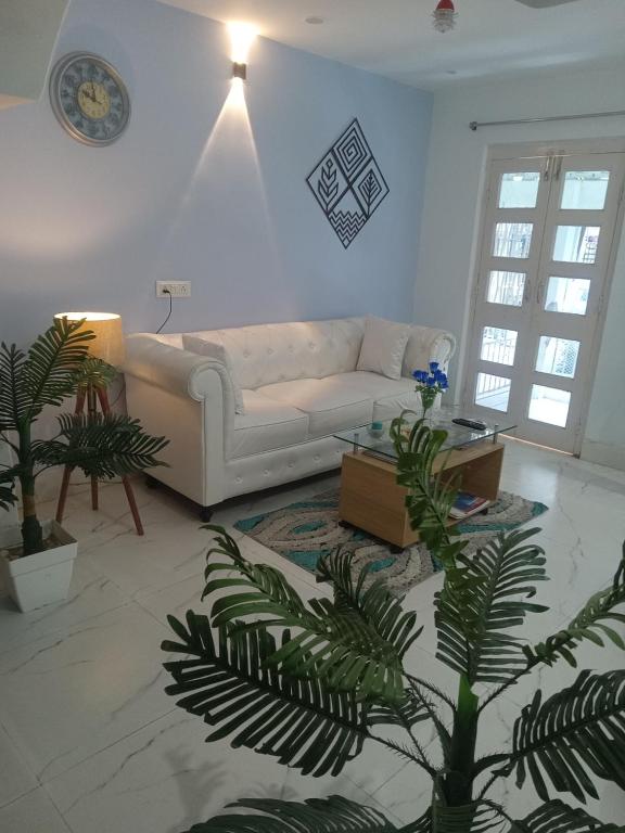 a living room with a white couch and a palm tree at Beautiful 1-bed Apartment-Suite Kolkata near Airport in Kolkata
