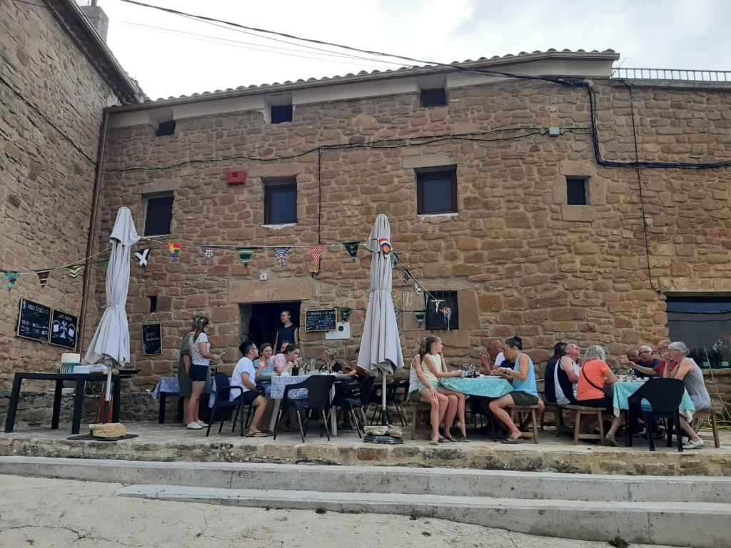 a group of people sitting at tables in front of a building at Albergue OasisTrails for pilgrims on Camino de Santiago in Villamayor de Monjardín
