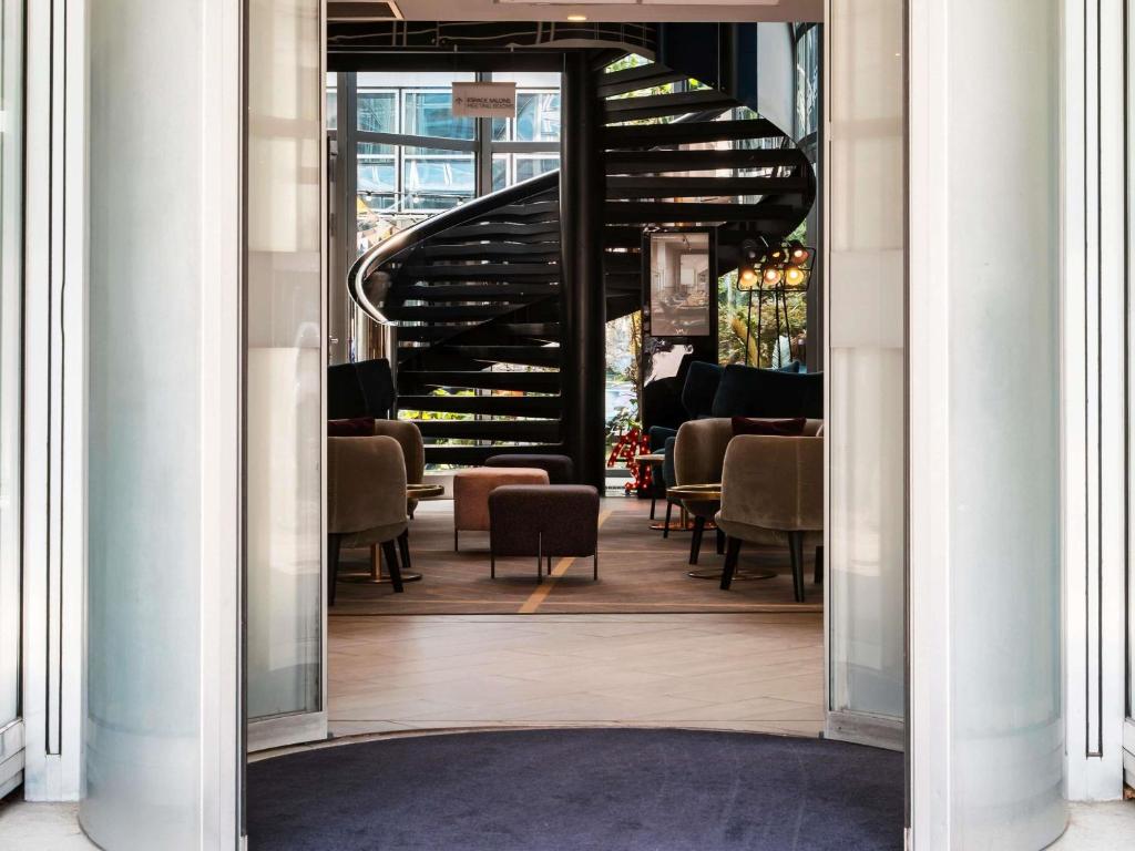 a doorway into a restaurant with chairs and stairs at Mercure Paris la Défense Grande Arche in Nanterre