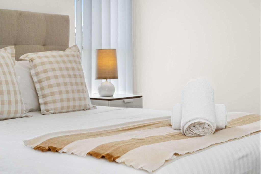 a white bed with a blanket and pillows on it at 4 bedroom luxury modern home near the beach and parks in Alkimos
