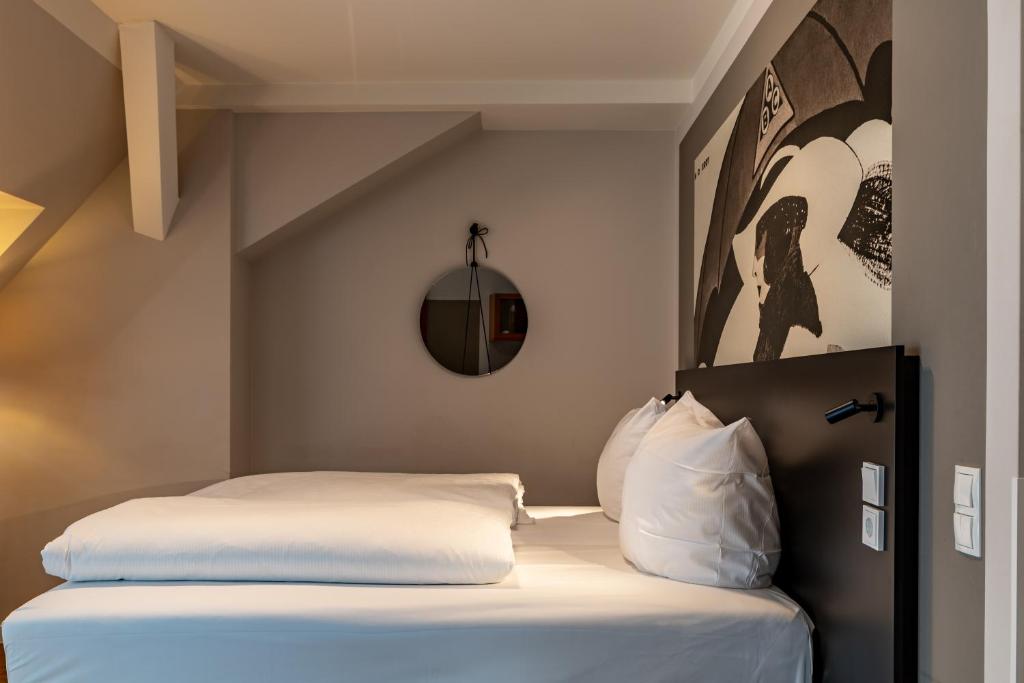 a bed with white sheets and pillows in a room at LIKESTAY Premium Baden-Baden - ehemals Batschari Palais in Baden-Baden