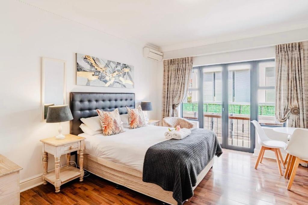 a bedroom with a bed and a balcony at Albatross Guest House Bantry Bay in Cape Town