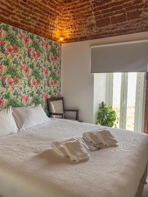 a bedroom with a white bed with a floral wall at AviStar by Portus Alacer in Avis