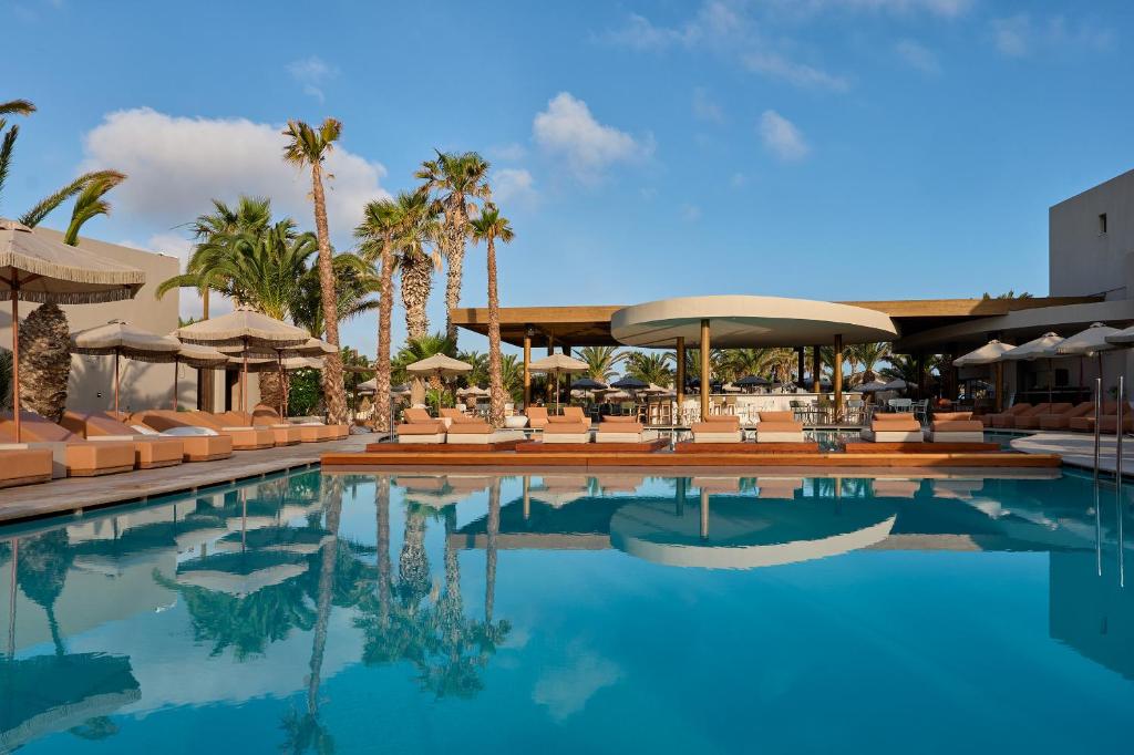 a pool at a resort with palm trees and umbrellas at Stella Village Seaside Hotel in Hersonissos
