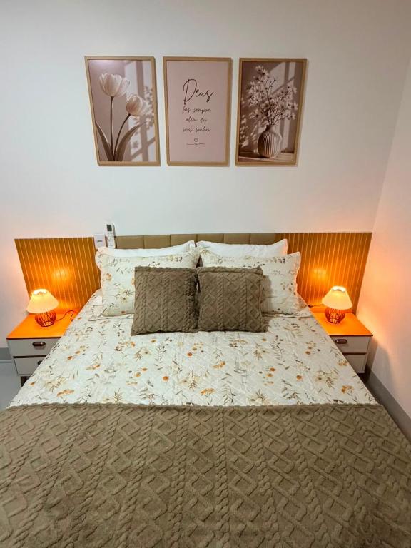 a bedroom with a large bed with three pictures on the wall at O mais charmoso do centro in Sinop