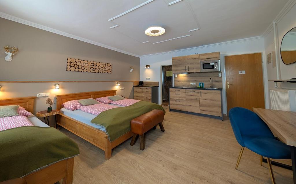 a bedroom with two beds and a table and a kitchen at Hotel Apartment Das Au- Gut in Hallein