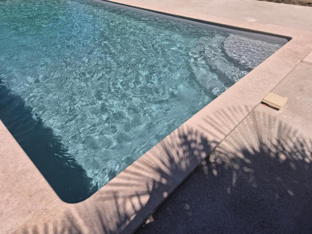 a swimming pool with a shadow of a tree at La Part'Thé in Crouy-sur-Cosson