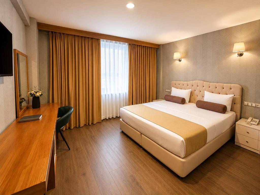 a hotel room with a large bed and a desk at Kuzen Otel in Istanbul