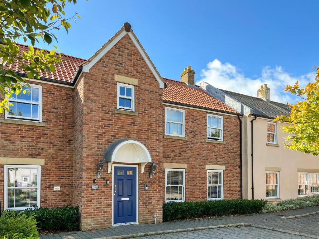 a red brick house with a blue door at Solara Breeze in Filey