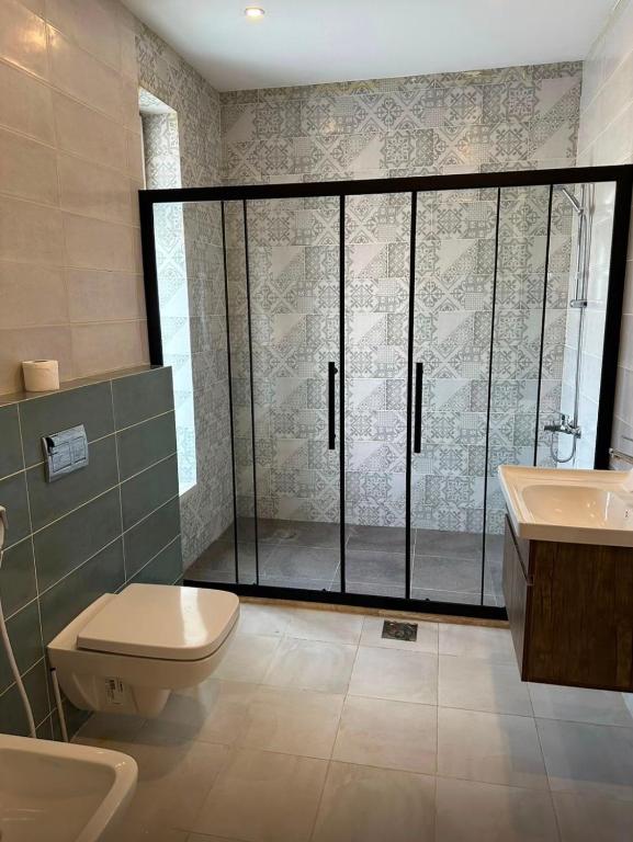 a bathroom with a shower and a toilet and a sink at Diva Chalet in Sowayma