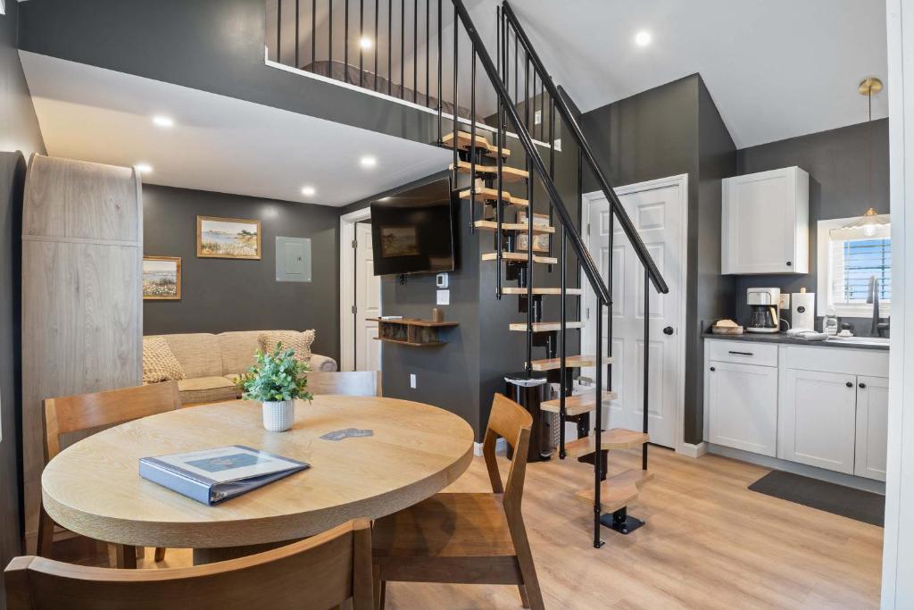 a dining room and kitchen with a table and a spiral staircase at Pelican Cliff Cottage - Tiny Home at Hampton Beach in Hampton