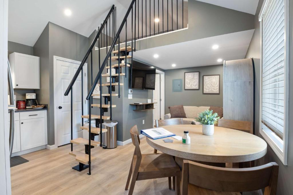 a kitchen and dining room with a table and a spiral staircase at Sandy Toes Cottage - Tiny Home at Hampton Beach in Hampton