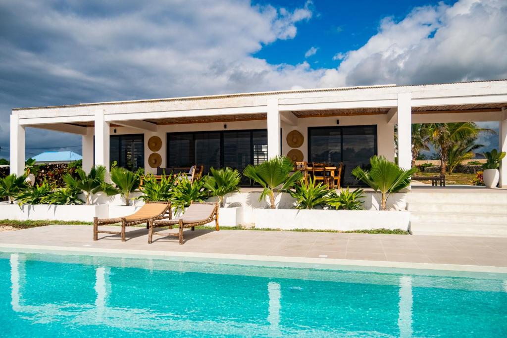 a house with a swimming pool in front of a house at Villa Kweli - Private Ocean Front Villa in Tongoni