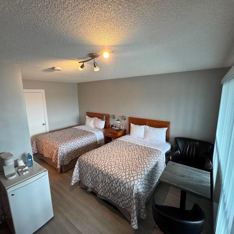 a hotel room with two beds and a chair at Motel Brise Marine in Shippagan