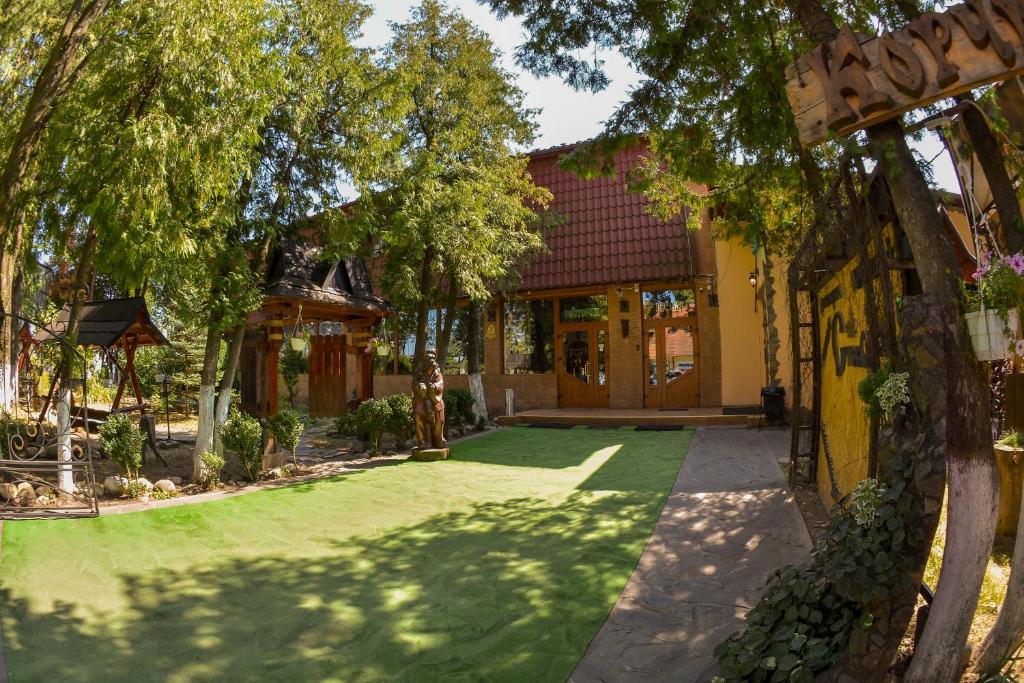 a house with a green lawn in front of it at Stizhok Hotel & Restaurant in Berkhomet-pe-Siret