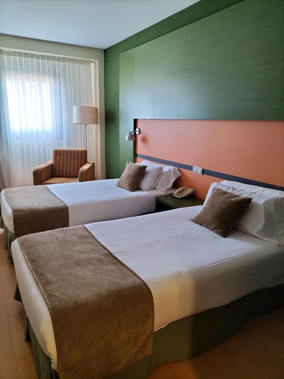 a hotel room with two beds and a chair at Hotel Naval Sestao in Sestao