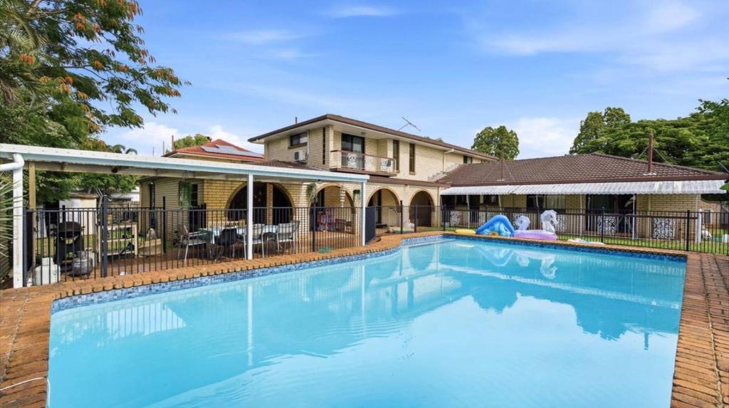 a large swimming pool in front of a house at 4BR big family house with huge pool in Brisbane