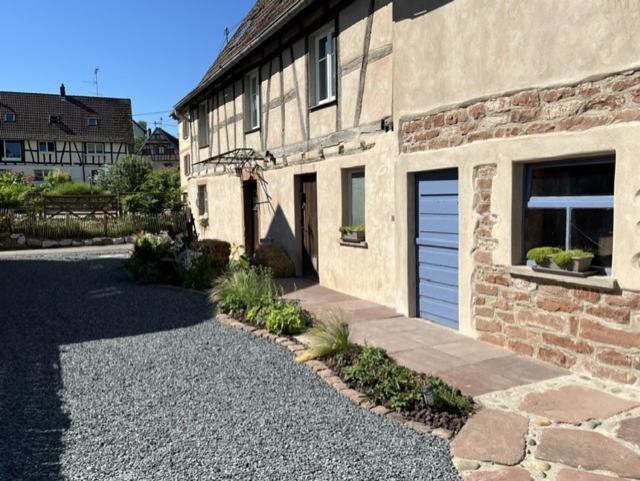 a brick building with a garage and a driveway at Gîte aux charmes d'Antan in Weinbourg
