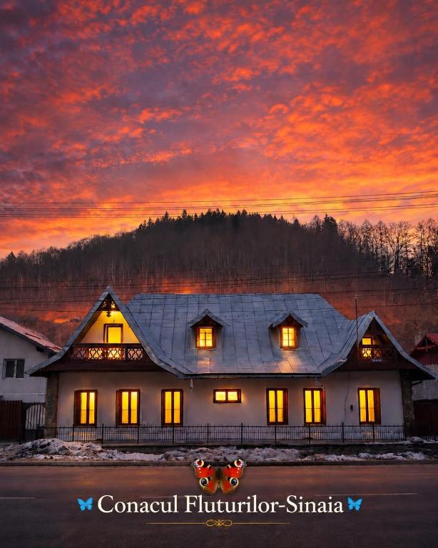 a house with a sunset in the background at Conacul Fluturilor in Sinaia
