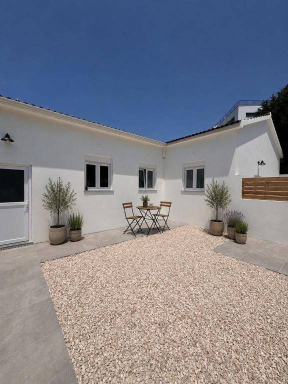 a white house with a table and potted plants at The Nook II, Lourinha in Lourinhã