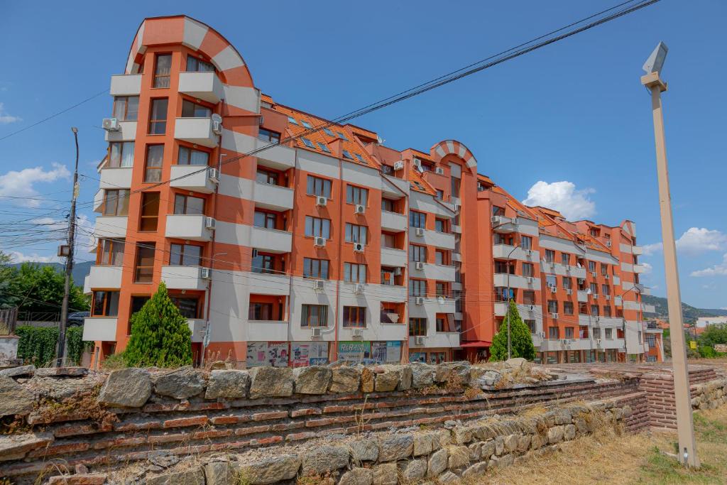 an orange and white apartment building with a stone wall at Антична панорама in Hisarya