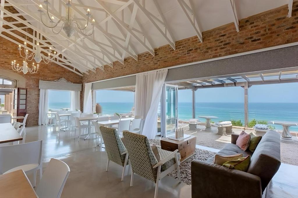 a living room with a couch and chairs and the ocean at Seeplaas Guesthouse in Great Brak River