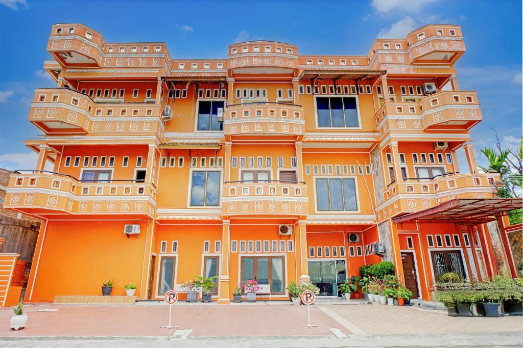 a large orange building with a lot of windows at Hotel O Kuta Alam Near Masjid Oman Al-Makmur Formerly Daka Hotel in Lheue