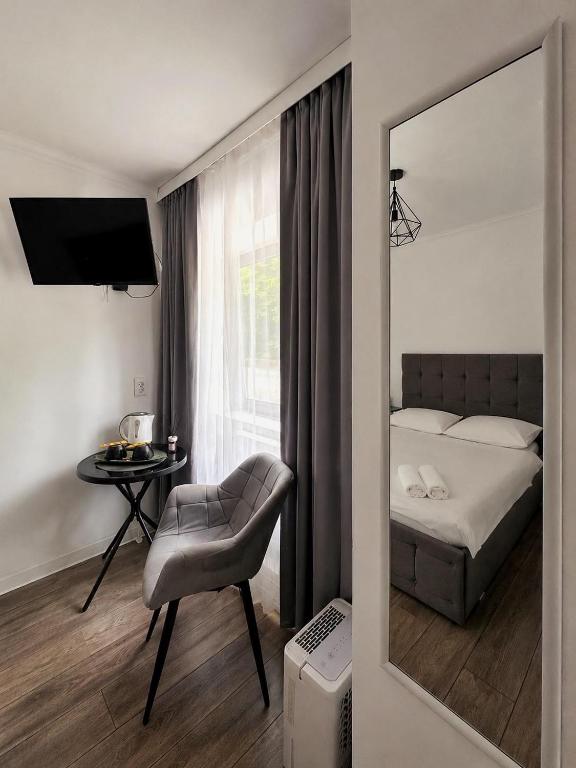 a bedroom with a bed and a chair and a mirror at Silver Residence Brașov in Braşov