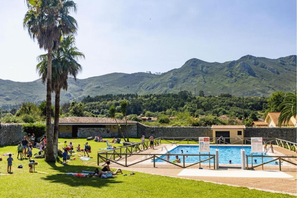 a group of people sitting in the grass by a pool at Kampaoh Bufones Pría in Garaña