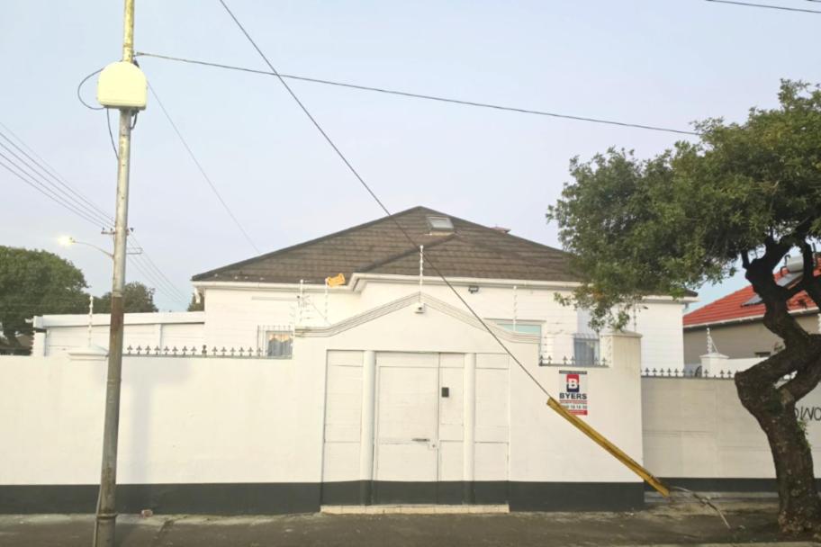 a white building with a large door and a tree at Goshen Lodge Goodwood in Goodwood