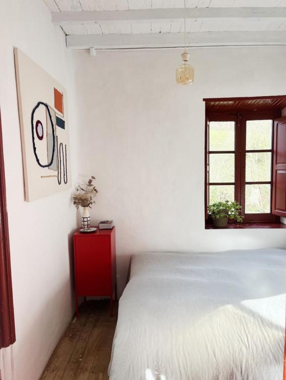 a white bedroom with a bed and a window at Cal Mengo in La Vega