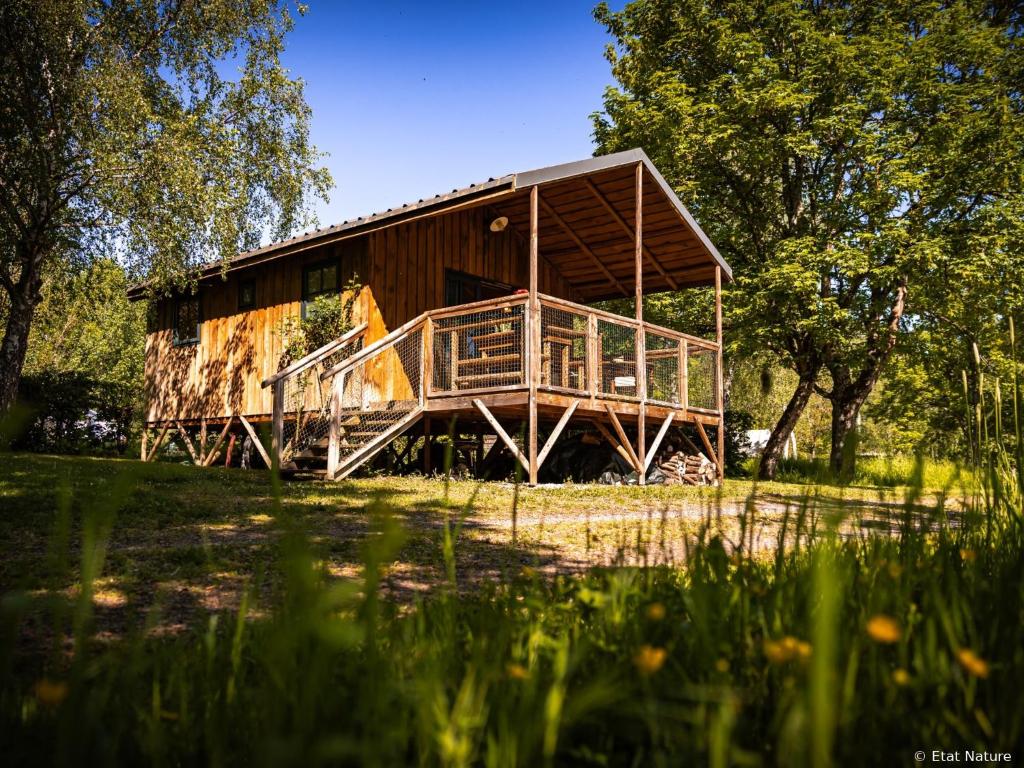 a large wooden building in the middle of a field at Tiny house - Cabane sur pilotis - Etat Nature in Magnières