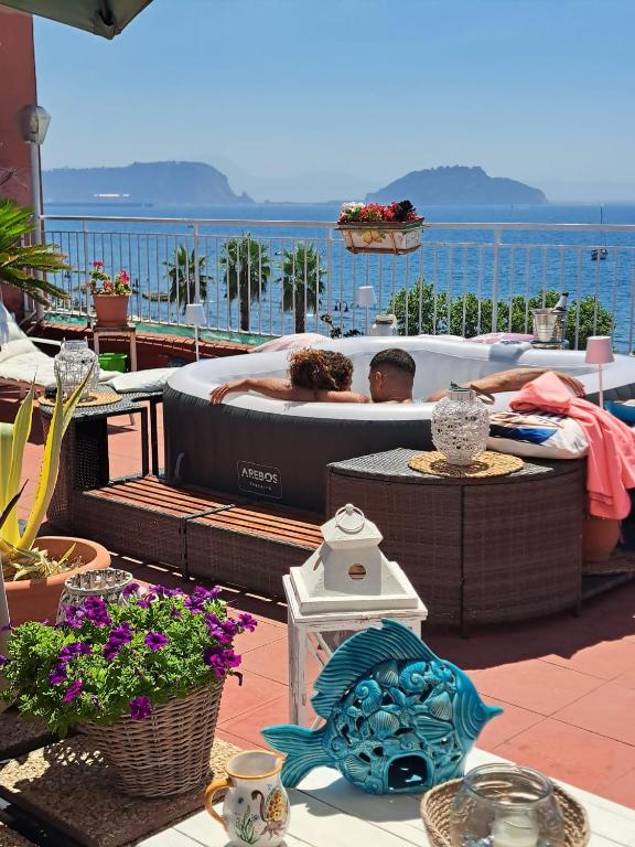 a man laying in a hot tub on a patio at Terrazza Miracapri in Pozzuoli
