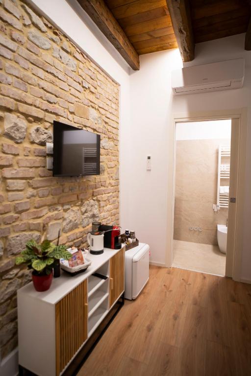 a living room with a stone wall and a tv at Domus Mirea in Aquiléia