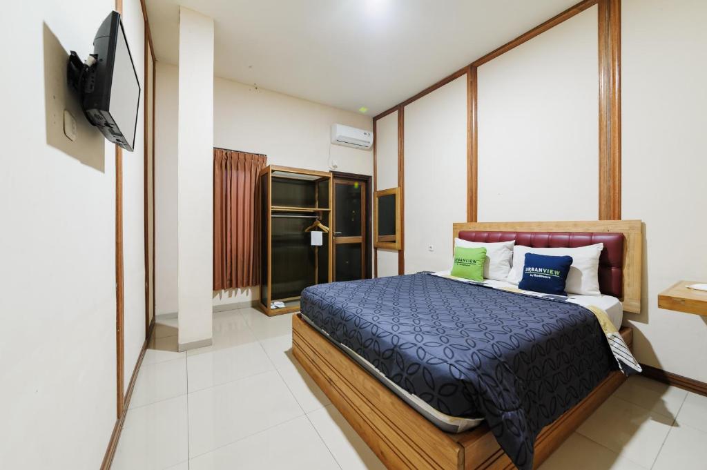 a bedroom with a bed and a flat screen tv at Urbanview Remington Hotel Palembang By RedDoorz in Palembang