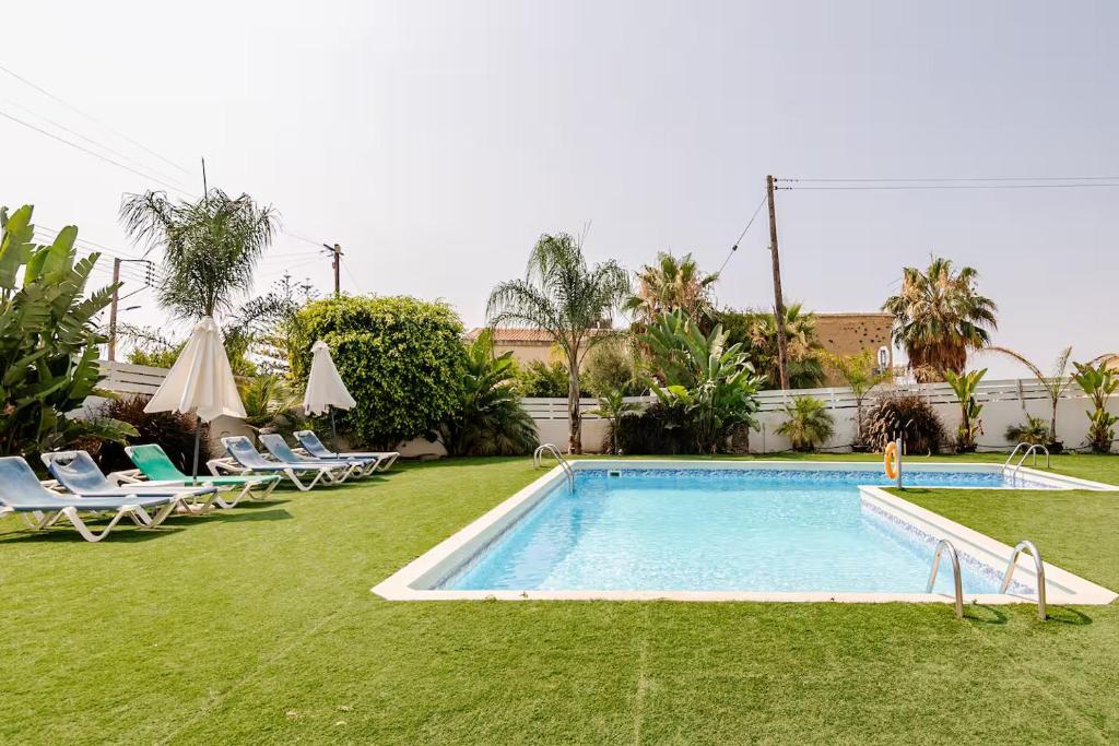 a swimming pool in a yard with lounge chairs at Oroklini Hills Modern Sea View Apartments in Oroklini