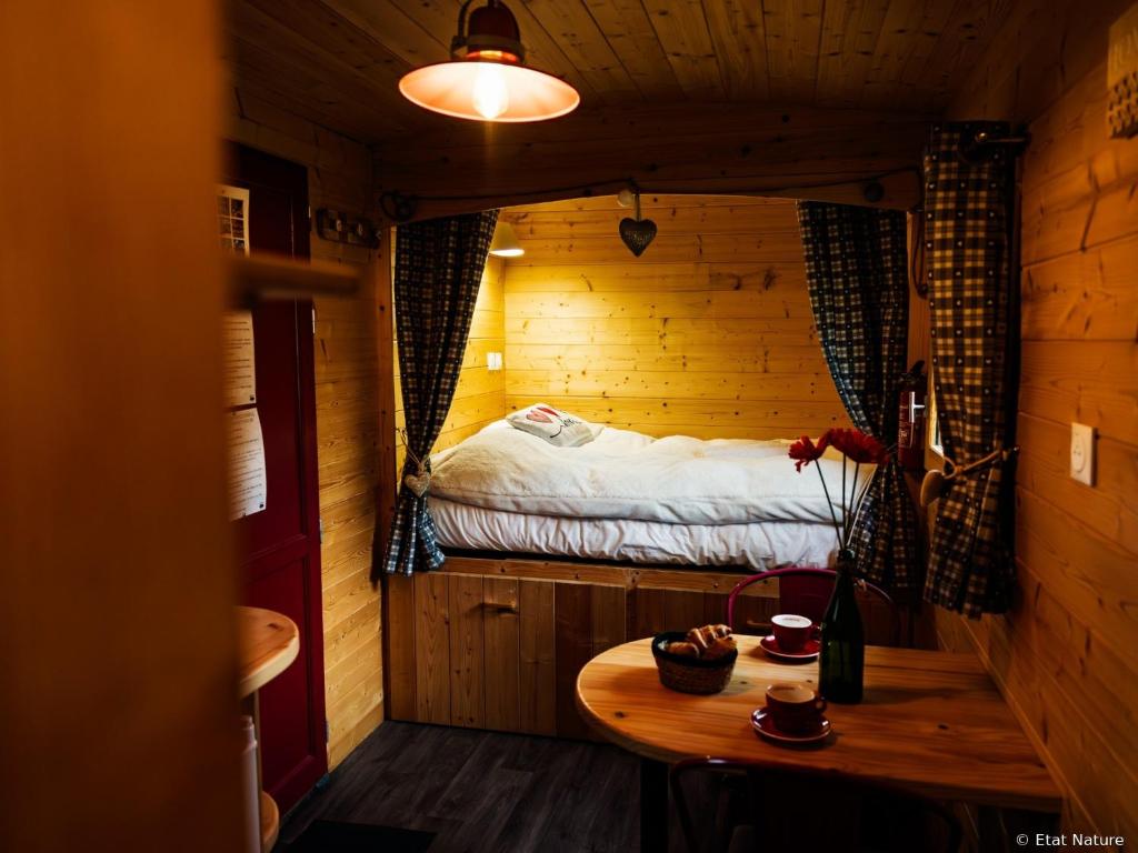 a small room with a bed and a wooden table at Roulotte - Etat Nature in Magnières
