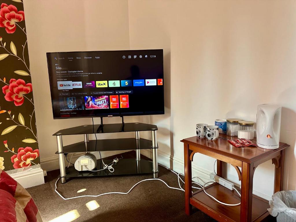 a living room with a flat screen tv and a table at 1 Bed & Breakfast West Brom in West Bromwich