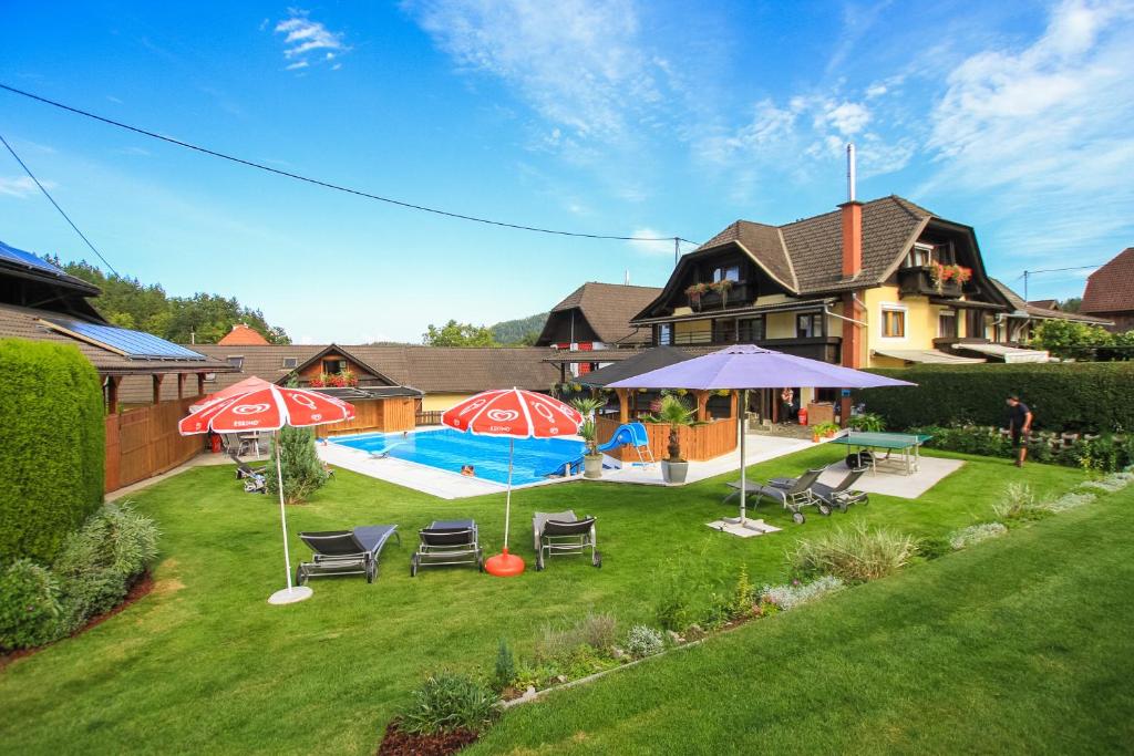 a backyard with a pool and umbrellas and a house at Gasthof Pisl in Krumpendorf am Wörthersee