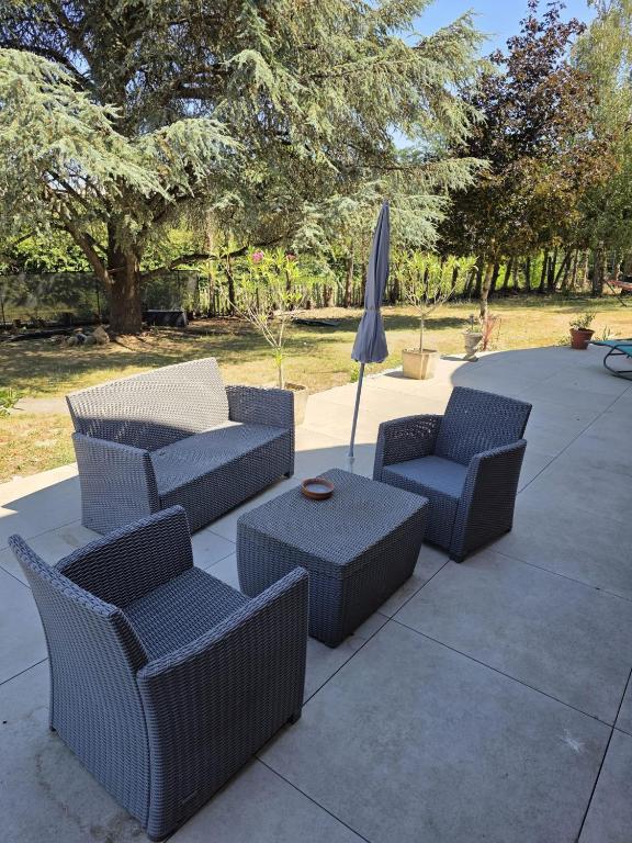 a patio with chairs and an umbrella and a table at Les Perriers in Chambray-lès-Tours