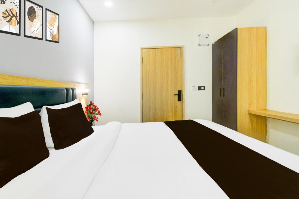 a bedroom with a large white bed with black pillows at Townhouse Aarav Business Hotel in Hyderabad