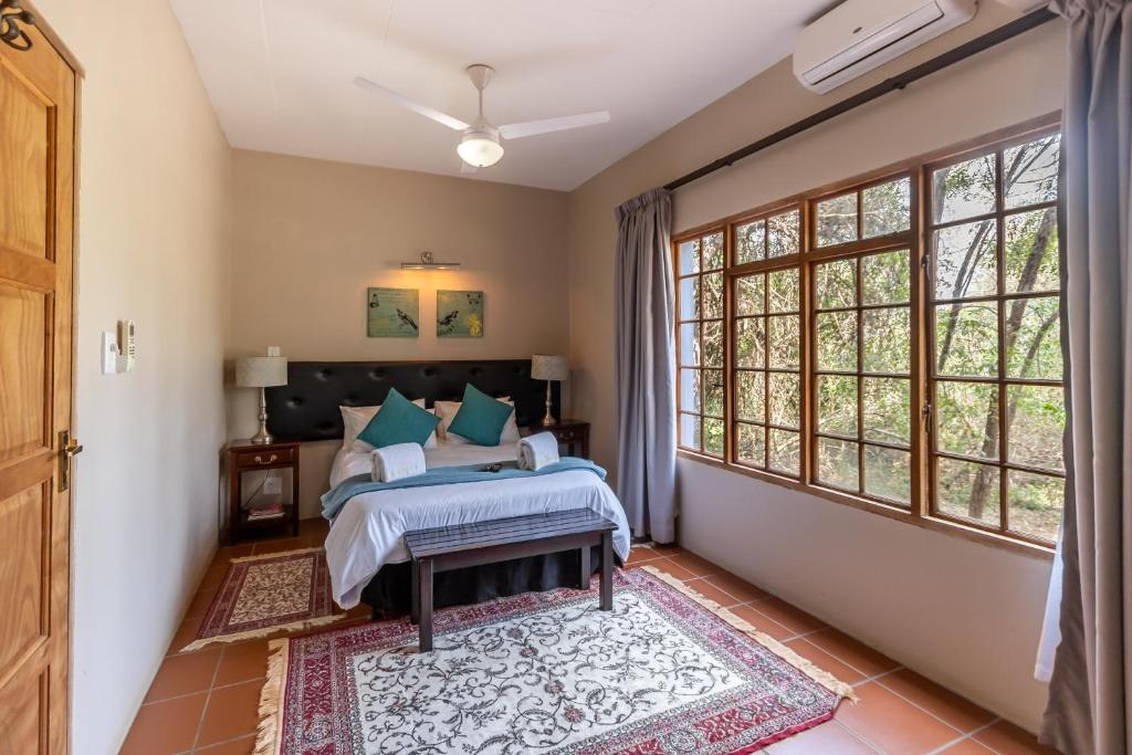 a bedroom with a bed and large windows at Ndumu Safari Resorts in Ingwavuma