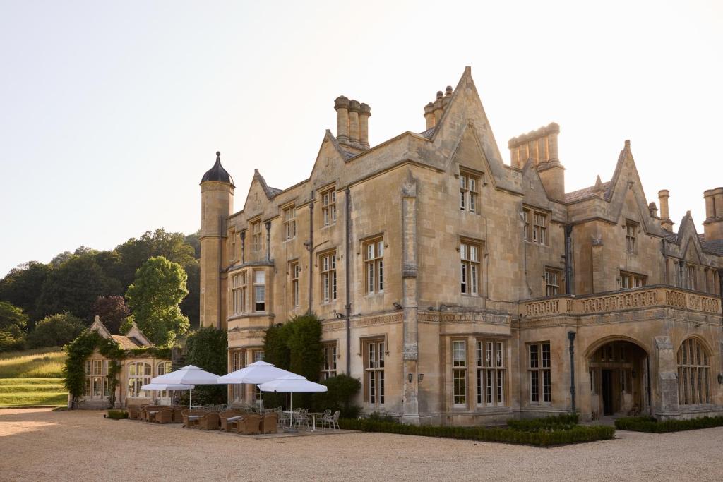an old castle with umbrellas in front of it at Dumbleton Hall in Broadway