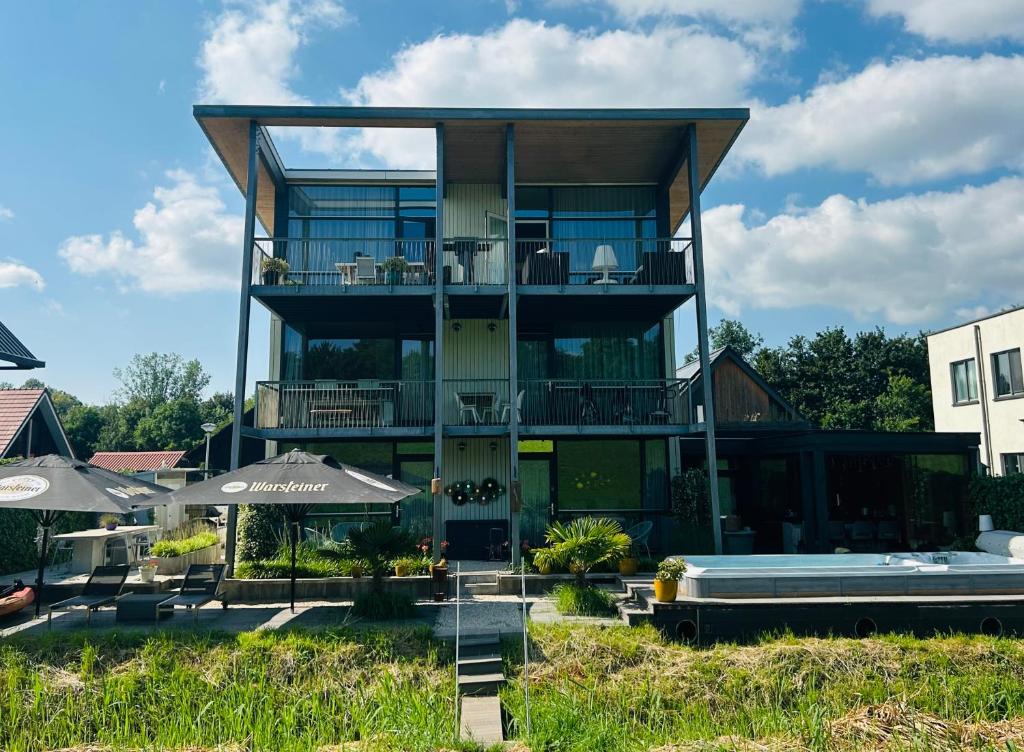 a large house with a balcony and a swimming pool at B&B Veluwemeer, jacuzzi, swim spa, sauna, steam bath and sandy beach in Biddinghuizen