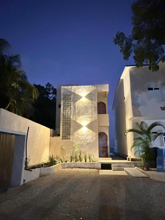 a white house with lights on the side of it at Departamentos blue Turquesa in Bacalar