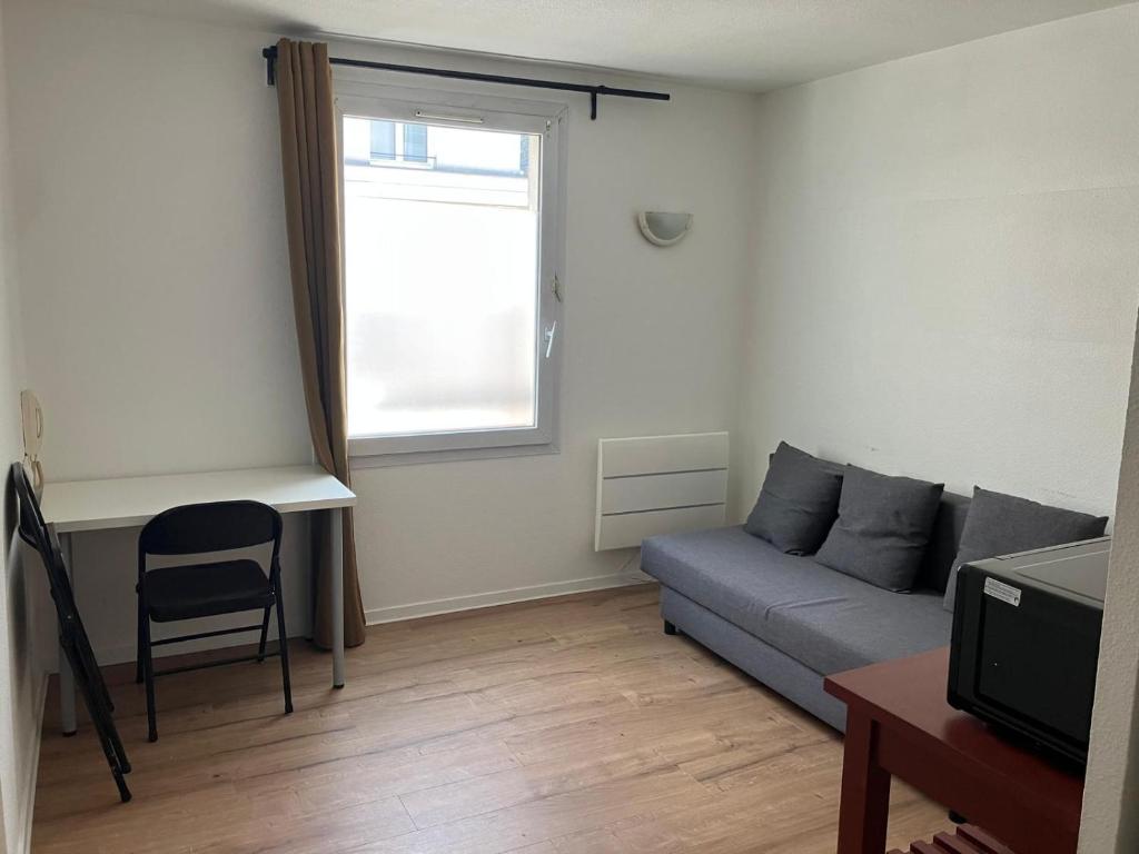 a living room with a couch and a window at Studio à Bussy St Georges in Bussy-Saint-Georges