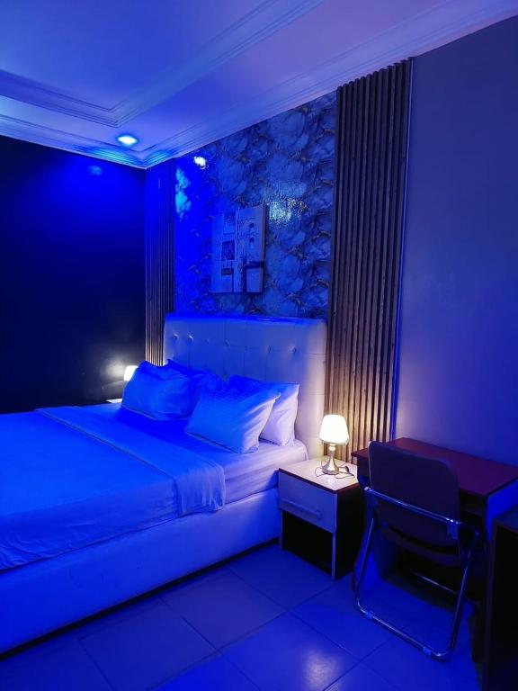 a blue room with a bed and a table and a chair at Pulville Boulevard Hotel in Suru Lere